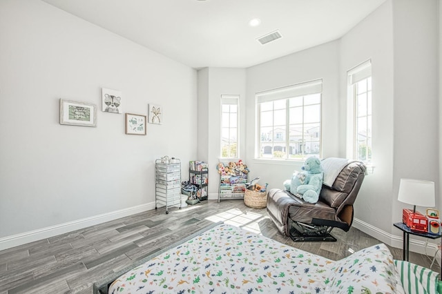 bedroom with wood finished floors, baseboards, multiple windows, and visible vents