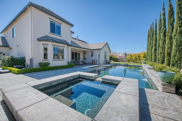 rear view of house featuring a patio area, a tile roof, a pool with connected hot tub, and stucco siding
