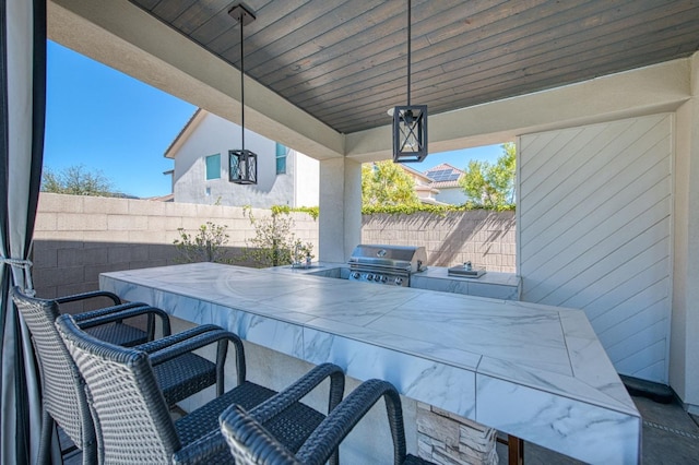 view of patio / terrace featuring fence, outdoor wet bar, area for grilling, and an outdoor kitchen