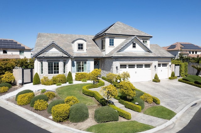 view of front of home with concrete driveway, stucco siding, fence, stone siding, and a gate