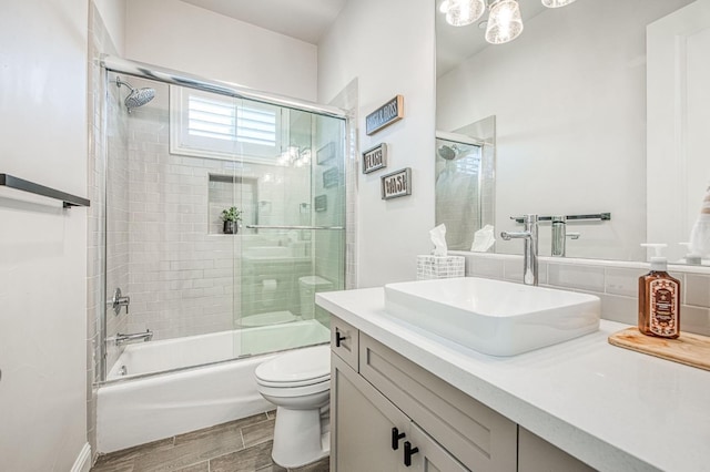 bathroom featuring toilet, shower / bath combination with glass door, vanity, and wood tiled floor