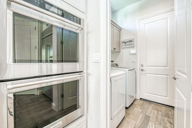 washroom with cabinet space, washer and dryer, and wood tiled floor