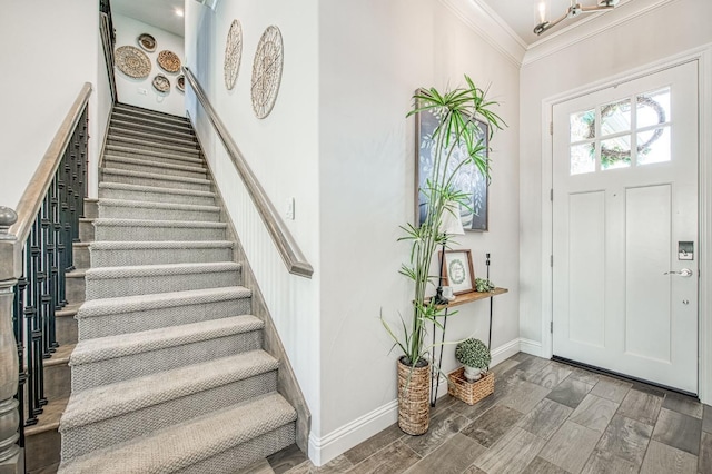 foyer entrance featuring ornamental molding, baseboards, stairway, and wood finished floors