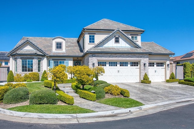 view of front of house with stucco siding, stone siding, an attached garage, aphalt driveway, and a tiled roof