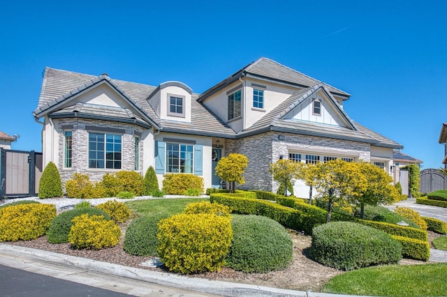 view of front of property with a tiled roof, stucco siding, stone siding, and a gate
