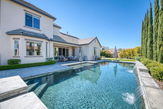 back of house featuring a fenced in pool, a patio, stucco siding, and a tiled roof
