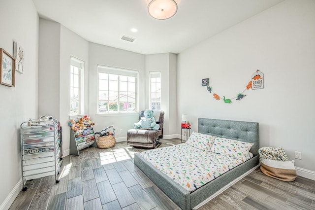 bedroom with visible vents, baseboards, and wood finish floors