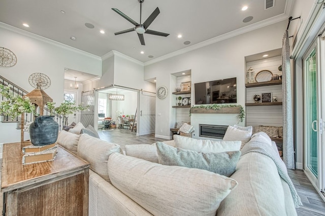 living room featuring a glass covered fireplace, recessed lighting, visible vents, ceiling fan with notable chandelier, and wood finished floors
