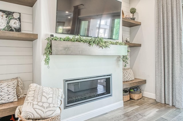 details featuring wood finished floors and a glass covered fireplace