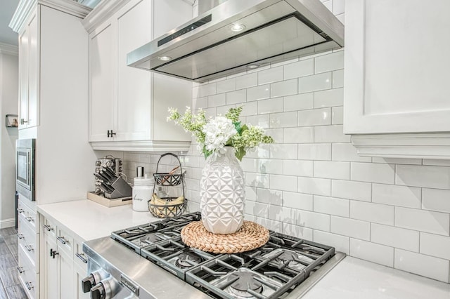 kitchen featuring stainless steel microwave, range, light countertops, exhaust hood, and white cabinets