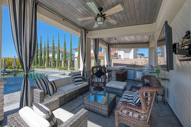 view of patio / terrace with ceiling fan, fence, an outdoor hangout area, a fenced in pool, and an outdoor kitchen