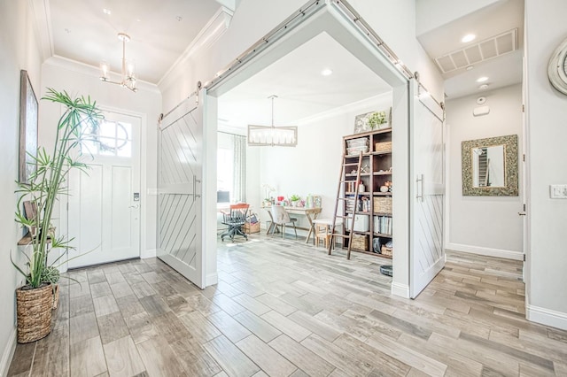 foyer entrance featuring a chandelier, crown molding, visible vents, and a barn door