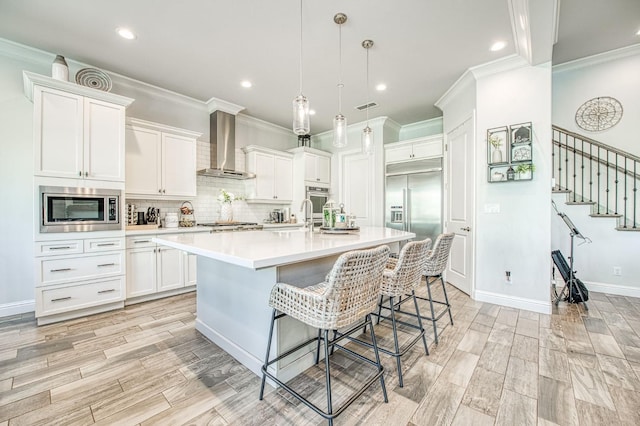 kitchen with built in appliances, light countertops, backsplash, visible vents, and wall chimney exhaust hood