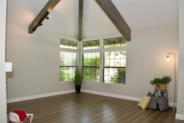 empty room featuring lofted ceiling with beams, wood finished floors, and baseboards