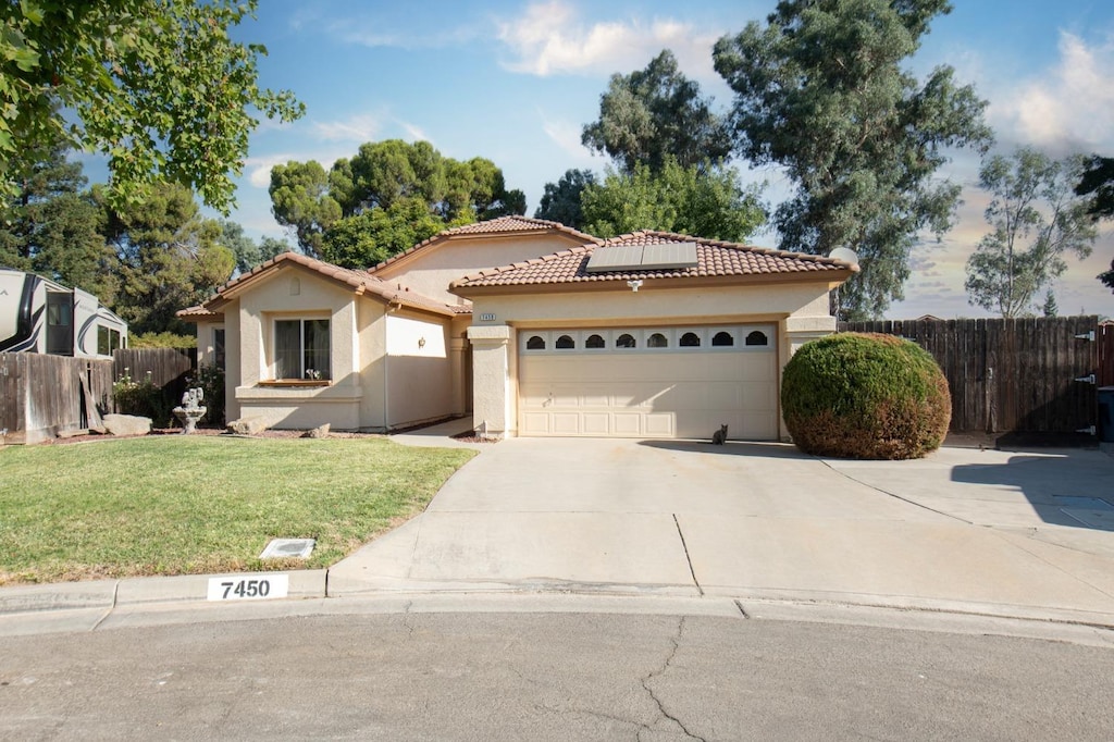 7450 N Gregory Ave, Fresno, CA 93722 - mediterranean / spanish-style house featuring driveway, a front yard, fence, and a tile roof