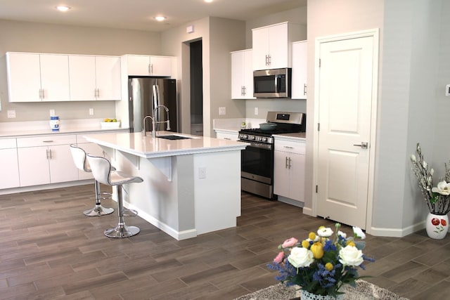 2060 N Walker Ln, Clovis, CA 93619 - kitchen with stainless steel appliances, a sink, dark wood finished floors, an island with sink, and light countertops