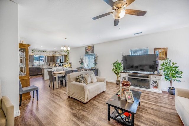 375 Amber Ln, Dinuba, CA 93618 - living area with visible vents, ceiling fan with notable chandelier, baseboards, and wood finished floors