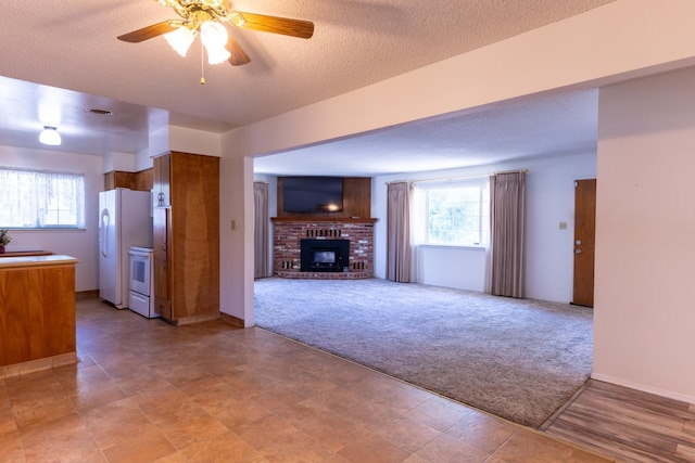 474 Dartmouth Ave, Coalinga, CA 93210 - unfurnished living room with a fireplace, light carpet, plenty of natural light, a ceiling fan, and a textured ceiling