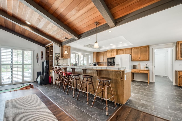 kitchen featuring a kitchen breakfast bar, white fridge with ice dispenser, black microwave, a peninsula, and wooden ceiling