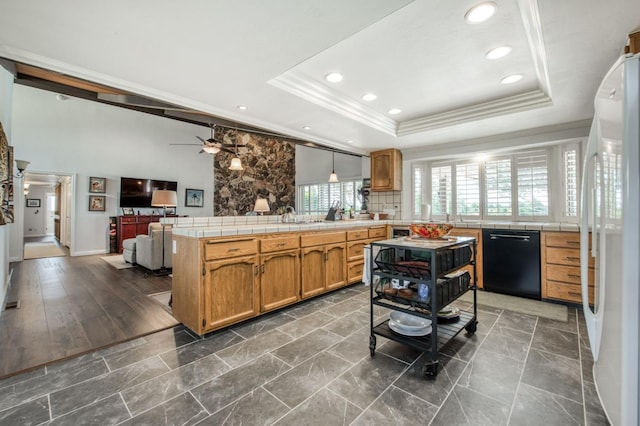 kitchen featuring a peninsula, dishwasher, freestanding refrigerator, and a raised ceiling