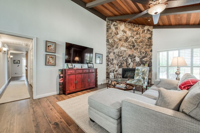 living area with baseboards, a fireplace, beam ceiling, ceiling fan, and hardwood / wood-style flooring