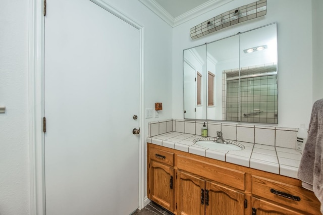 full bath with a tile shower, vanity, and ornamental molding