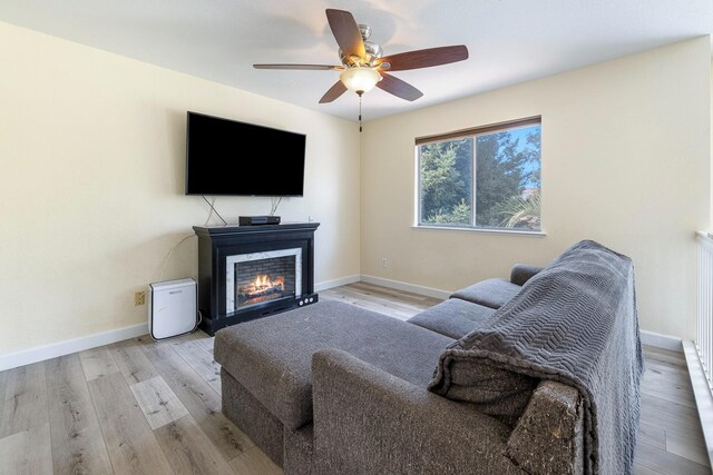 3232 Greenfield Ave, Clovis, CA 93611 - living room featuring ceiling fan, a lit fireplace, and light wood-type flooring