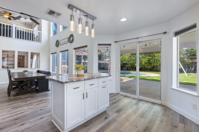 3232 Greenfield Ave, Clovis, CA 93611 - kitchen featuring ceiling fan, light stone countertops, white cabinetry, light wood-style flooring, and a textured ceiling