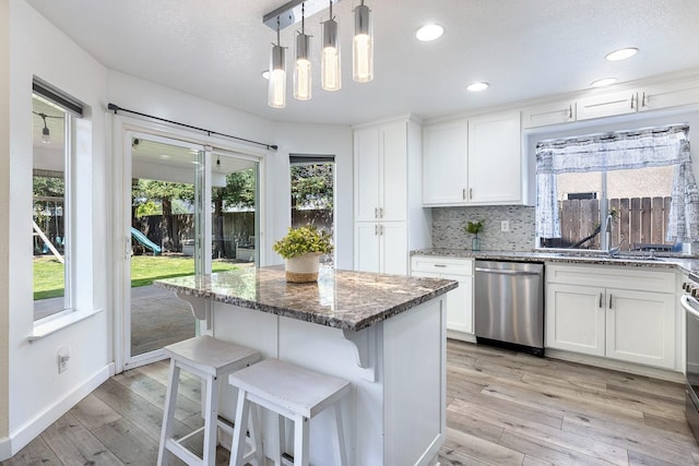 3232 Greenfield Ave, Clovis, CA 93611 - kitchen featuring stainless steel dishwasher, dark stone countertops, white cabinets, light wood-type flooring, and backsplash