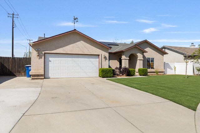 683 W Forest St, Kingsburg, CA 93631 - ranch-style house featuring driveway, fence, roof mounted solar panels, a front lawn, and stucco siding