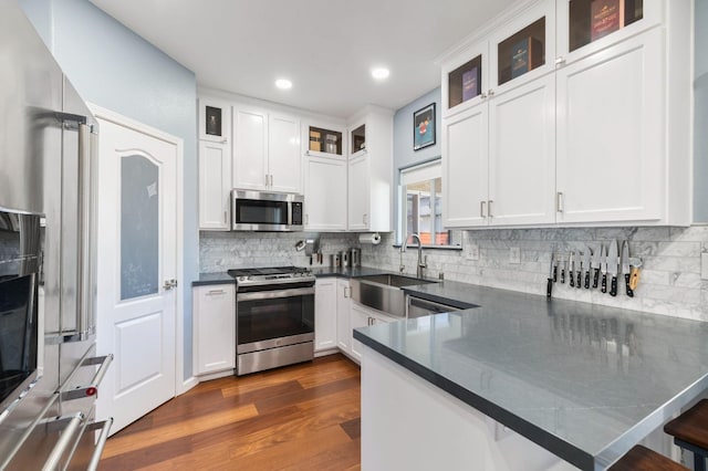 683 W Forest St, Kingsburg, CA 93631 - kitchen with dark countertops, appliances with stainless steel finishes, a sink, a peninsula, and white cabinetry