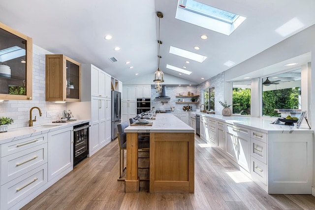 8683 N Colfax Ave, Fresno, CA 93720 - kitchen featuring a sink, vaulted ceiling with skylight, beverage cooler, wall chimney exhaust hood, and decorative backsplash