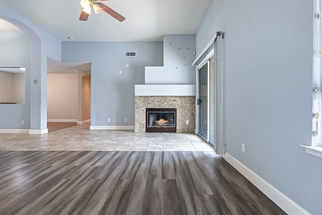 6187 W Alluvial Ave, Fresno, CA 93722 - unfurnished living room with a ceiling fan, wood finished floors, a fireplace, and arched walkways