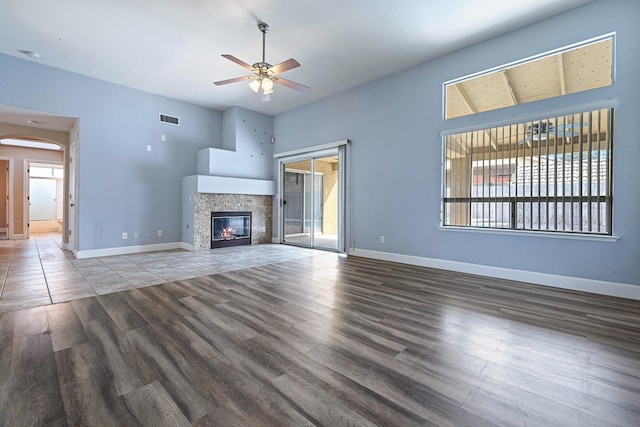 6187 W Alluvial Ave, Fresno, CA 93722 - unfurnished living room featuring wood finished floors, ceiling fan, a tile fireplace, and arched walkways