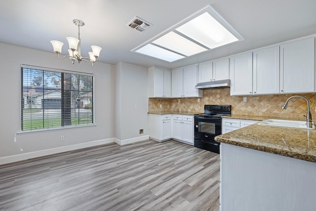 6187 W Alluvial Ave, Fresno, CA 93722 - kitchen with black / electric stove, under cabinet range hood, white cabinets, decorative backsplash, and light wood finished floors