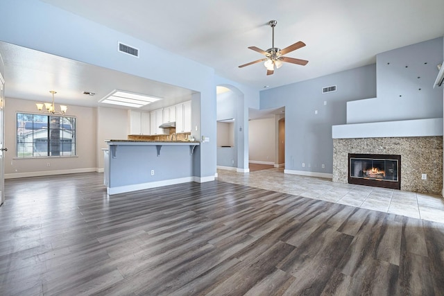 6187 W Alluvial Ave, Fresno, CA 93722 - unfurnished living room with a ceiling fan, a chandelier, wood finished floors, and a tile fireplace