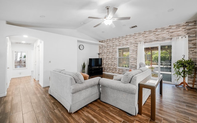 living area featuring arched walkways, lofted ceiling, ceiling fan, and wood finished floors