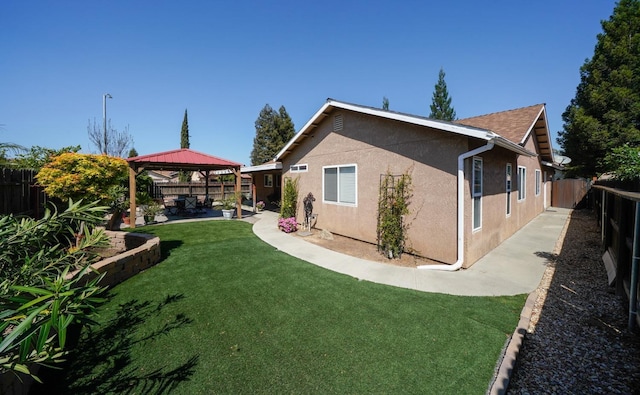 rear view of property featuring a gazebo, stucco siding, and a patio