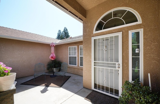 property entrance featuring stucco siding and a patio