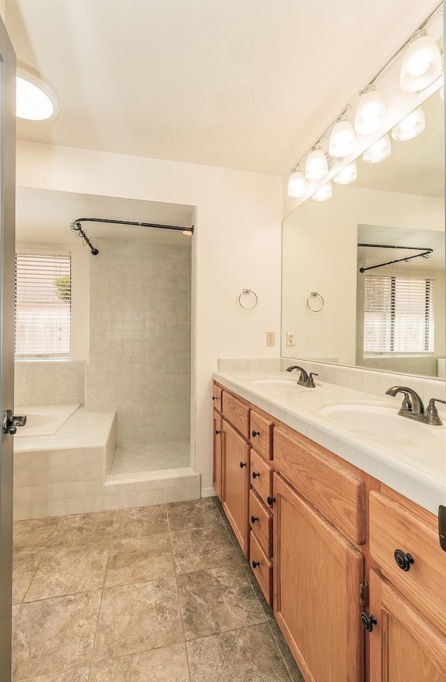 full bath featuring a relaxing tiled tub, a sink, double vanity, and tiled shower