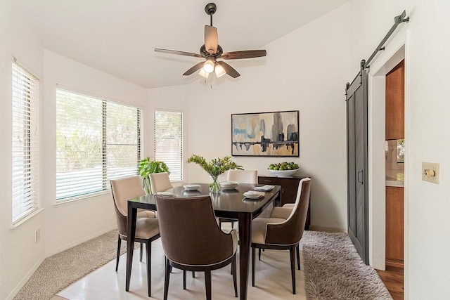 dining room featuring a barn door, vaulted ceiling, baseboards, and ceiling fan