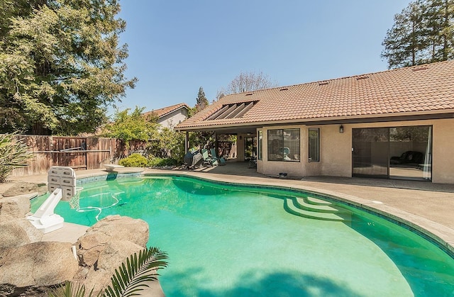 view of swimming pool featuring a diving board, fence, a patio, and a fenced in pool