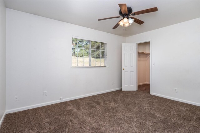 31200 Revis Rd, Coarsegold, CA 93614 - unfurnished bedroom with a spacious closet, dark colored carpet, baseboards, and a ceiling fan