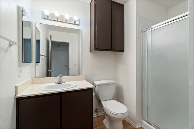 bathroom with a shower stall, wood finished floors, vanity, and toilet