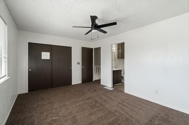 unfurnished bedroom featuring a closet, dark colored carpet, a textured ceiling, and baseboards