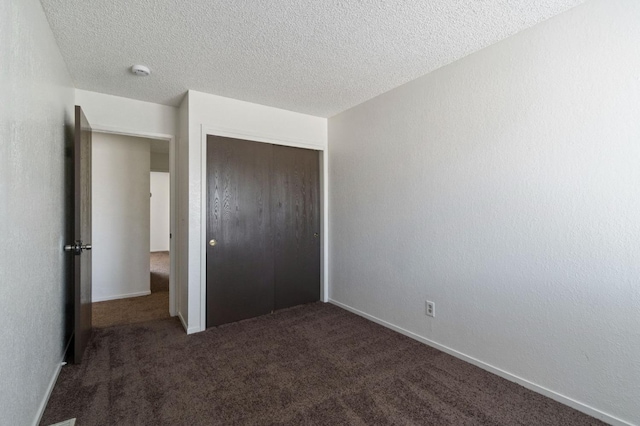 unfurnished bedroom featuring baseboards, a closet, a textured ceiling, and carpet floors