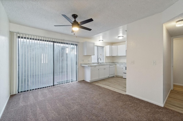 kitchen featuring a textured ceiling, a ceiling fan, white cabinets, light carpet, and dishwasher