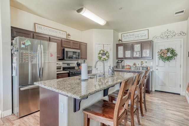 2960 3rd St, Sanger, CA 93657 - kitchen with stainless steel appliances, a breakfast bar area, a sink, light wood finished floors, and light stone countertops