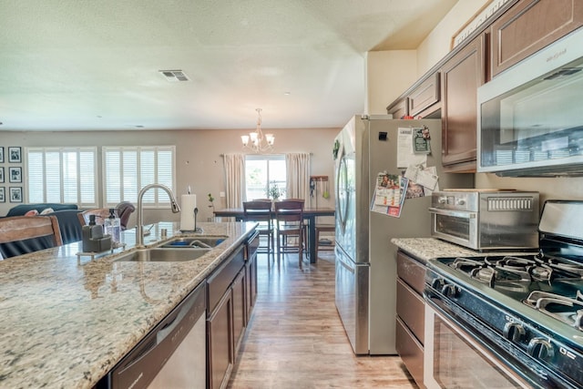 2960 3rd St, Sanger, CA 93657 - kitchen featuring appliances with stainless steel finishes, a sink, a chandelier, light wood-type flooring, and light stone counters