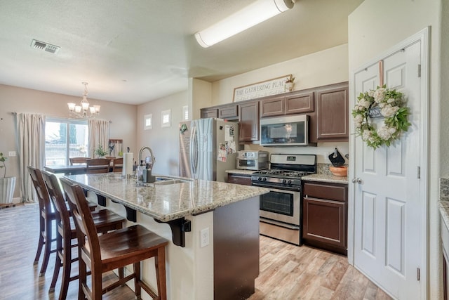 2960 3rd St, Sanger, CA 93657 - kitchen featuring appliances with stainless steel finishes, a sink, a chandelier, light wood-type flooring, and a center island with sink